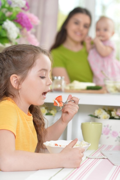 Linda garota comendo deliciosa salada fresca na cozinha