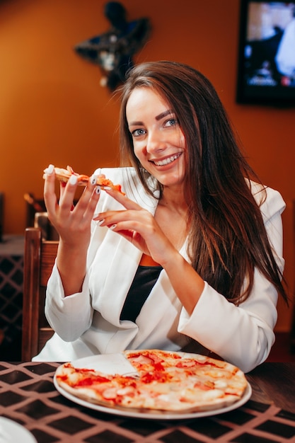 Linda garota comendo pizza em restaurante