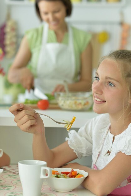 linda garota comendo salada na cozinha