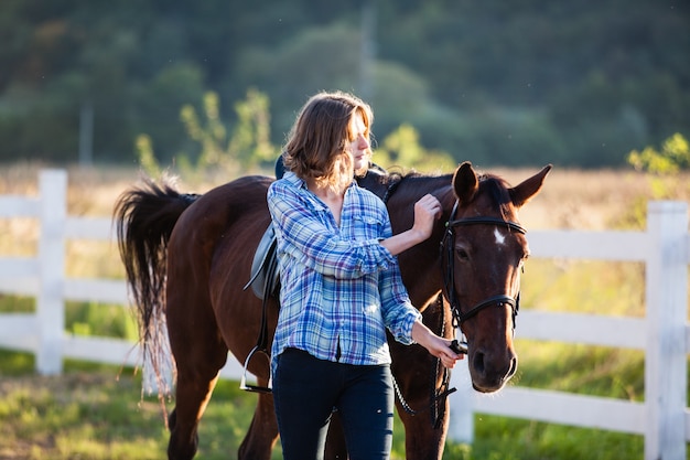 Linda garota conduzindo seu cavalo marrom na fazenda