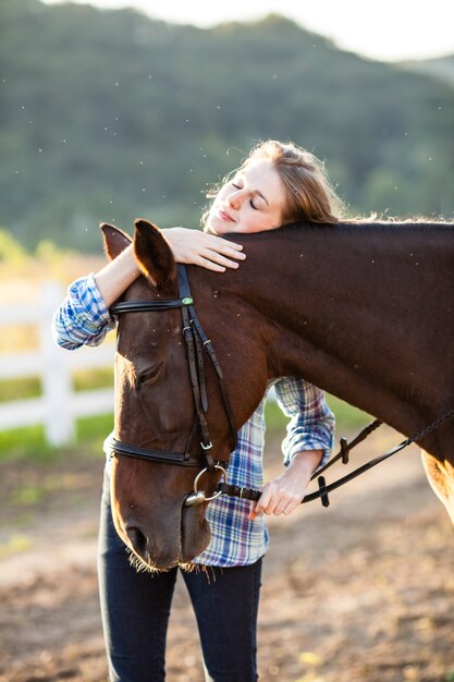 Linda garota conduzindo seu cavalo marrom na fazenda