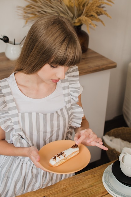 Linda garota confeitaria ou dona de casa segurando um prato com eclairs Curso de culinária ou confeitaria