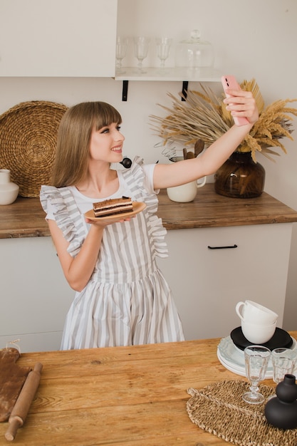 Linda garota confeiteira ou dona de casa faz selfie com bolo O conceito de um blog de culinária