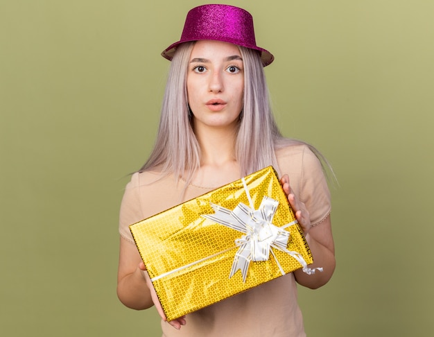 Linda garota confusa com chapéu de festa segurando uma caixa de presente