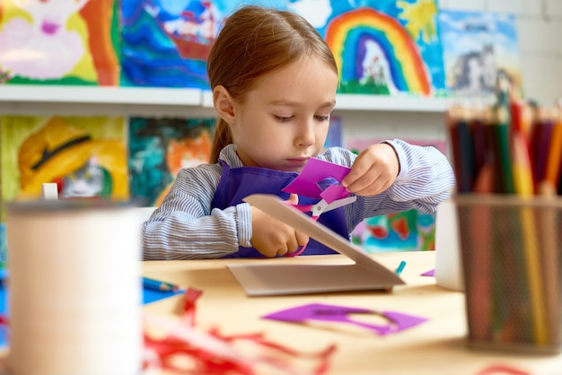 Linda garota cortar papel na classe de artesanato