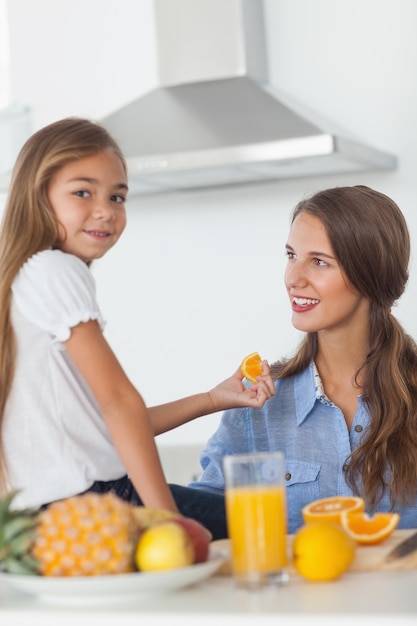 Linda garota dando um segmento de laranja para sua mãe