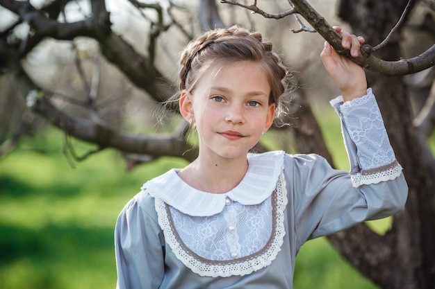 Linda garota de 6 a 7 anos de idade, posando no jardim. Páscoa. gosta de primavera e calor. Belo jardim de primavera. Conceito de infância, paz e felicidade feliz. Flor aromática e vintage retrô.