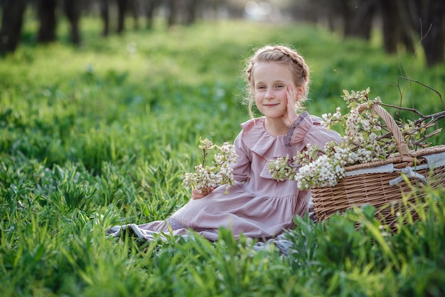 Linda garota de 6 a 7 anos de idade, posando no jardim. Páscoa. gosta de primavera e calor. Belo jardim de primavera. Conceito de infância, paz e felicidade feliz. Flor aromática e vintage retrô.