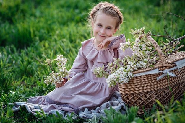 Linda garota de 6 a 7 anos de idade, posando no jardim. Páscoa. gosta de primavera e calor. Belo jardim de primavera. Conceito de infância, paz e felicidade feliz. Flor aromática e vintage retrô.