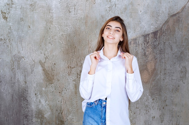 Linda garota de cabelo comprido com blusa branca, posando com uma expressão feliz