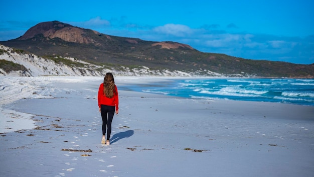 linda garota de cabelos compridos caminha ao pôr do sol na famosa praia da baía da sorte, na austrália ocidental