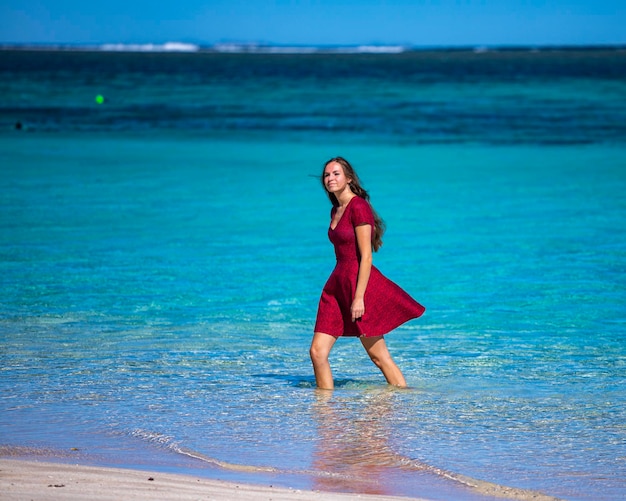 linda garota de cabelos compridos em um vestido encharca os pés na água em turquesa bay oeste da austrália