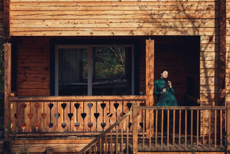 Foto linda garota de cabelos compridos posando perto de casa de log.