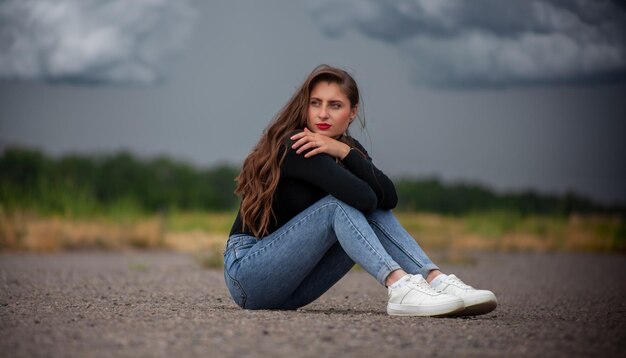 Foto linda garota de jeans no fundo das nuvens de tempestade