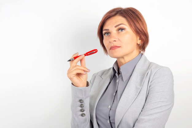 Linda garota de negócios jovem com uma caneta vermelha na mão em uma superfície branca