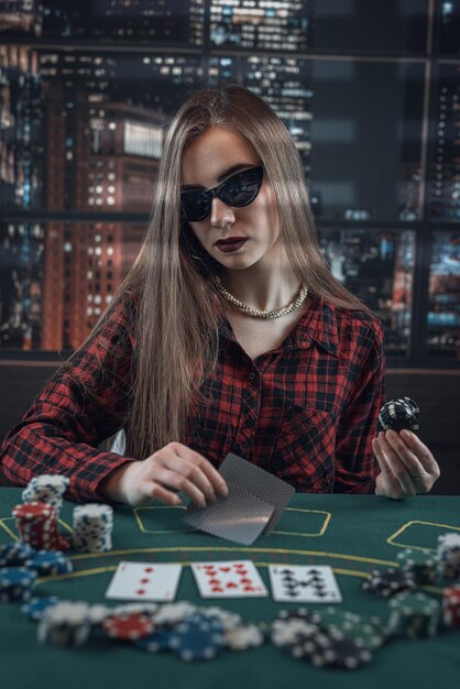 Linda garota de óculos escuros joga pôquer cara de pôquer
