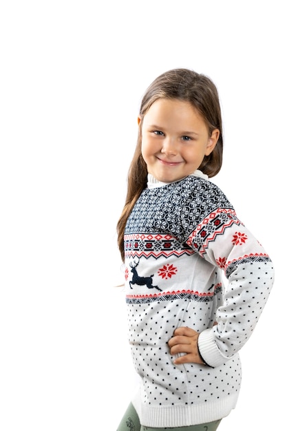 Linda garota de seis anos no suéter de malha branca de Natal com renas posa com a mão na cintura isola ...