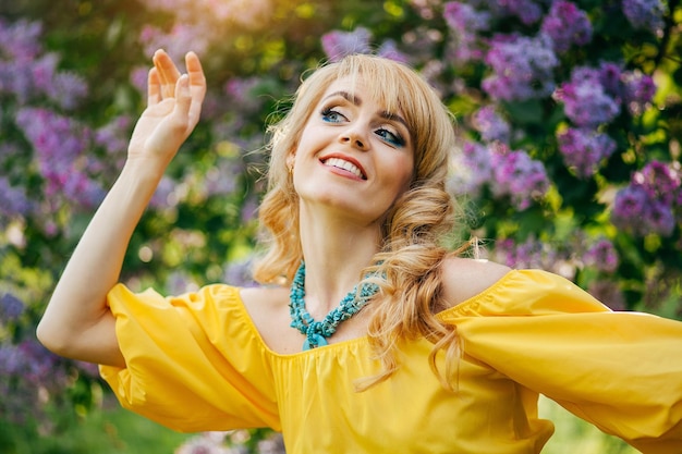 Linda garota de vestido amarelo no jardim florescendo