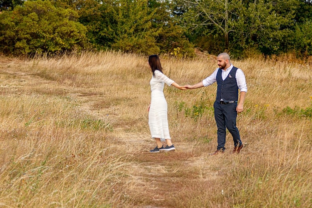 Linda garota de vestido branco e um cara em um campo contra um céu azul com nuvens