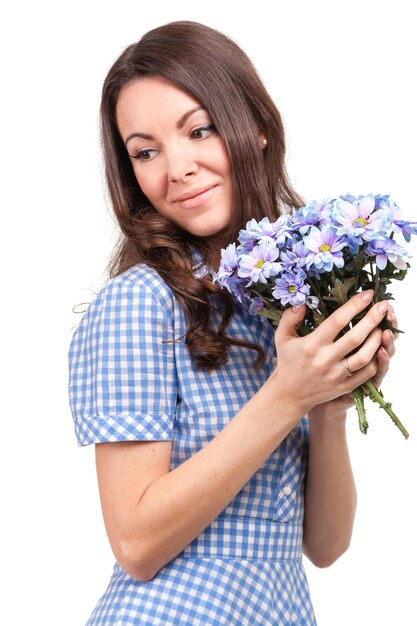 Linda garota de vestido em uma gaiola azul com flores crisântemos nas mãos em um fundo branco