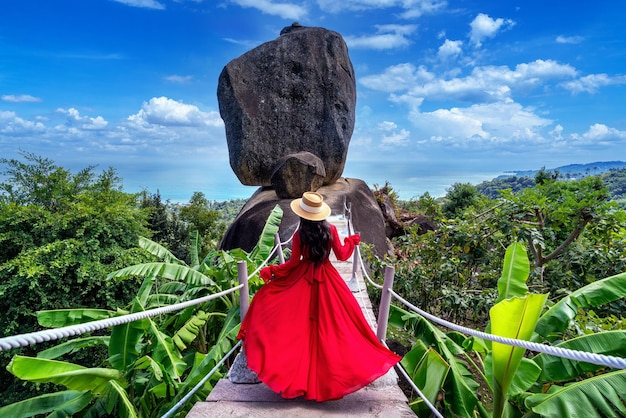 Linda garota de vestido vermelho andando na pedra de sobreposição em koh samui tailândia