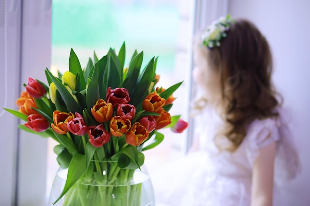 Linda garota de vestidos brancos com um magnífico buquê das primeiras tulipas dia internacional da mulher menina com tulipas
