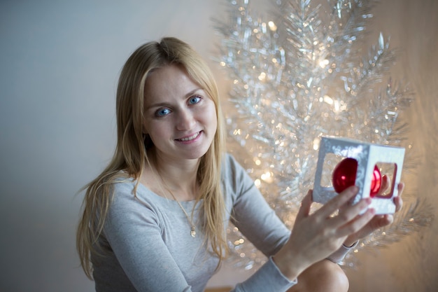 Linda garota decora uma árvore de Natal. Preparação para o feriado