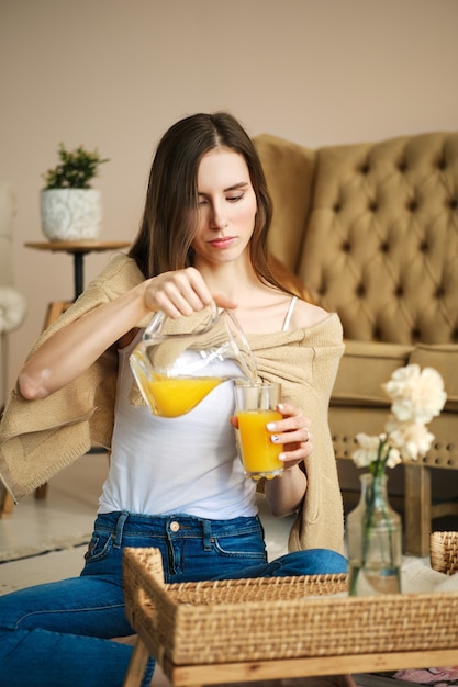 Linda garota despeja suco no copo da jarra