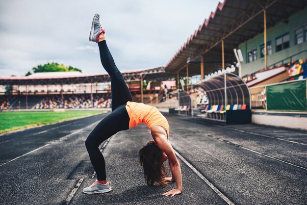 Linda garota desportiva mostra exercícios de alongamento ao ar livre