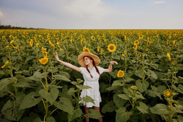 Linda garota doce com um chapéu de palha em um vestido branco um campo de girassóis agricultura paisagem