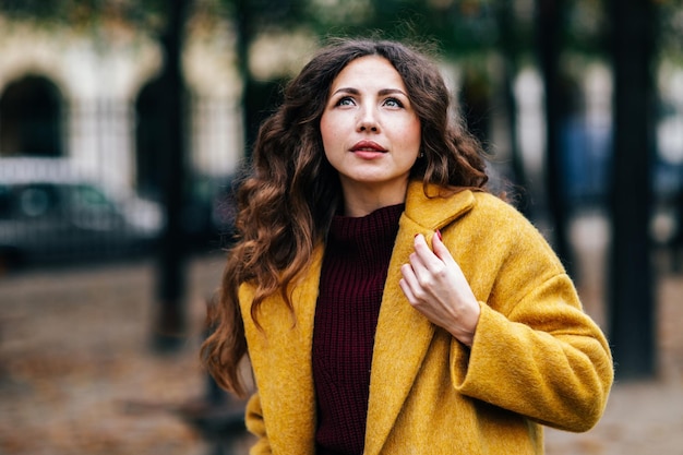 Linda garota elegante com um casaco amarelo caminha pelas ruas de Paris
