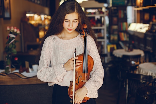 Linda garota elegante em pé em um café com violino