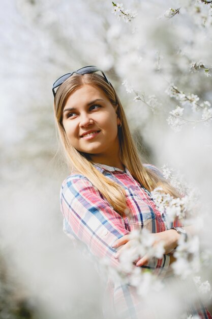 Linda garota em árvores floridas no início da primavera. Sol brilhante e natureza