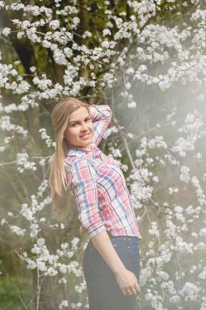 Linda garota em árvores floridas no início da primavera. Sol brilhante e natureza