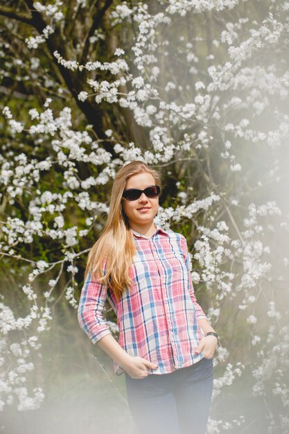 Linda garota em árvores floridas no início da primavera. Sol brilhante e natureza