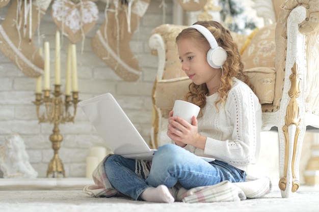 Linda garota em fones de ouvido com laptop no Natal