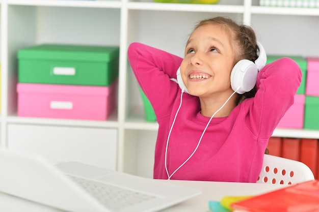 Linda garota em fones de ouvido usando laptop em casa