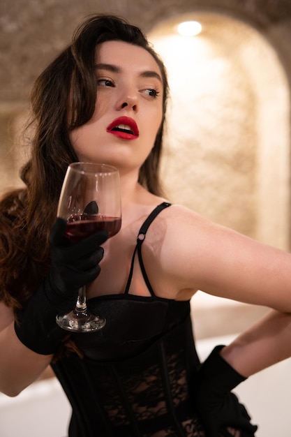 Linda garota em lingerie erótica sentada no banheiro com uma taça de vinho