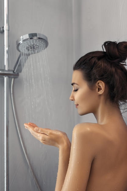 Foto linda garota em pé no chuveiro. retrato de mulher feliz mestiça caucasiana magro asiática