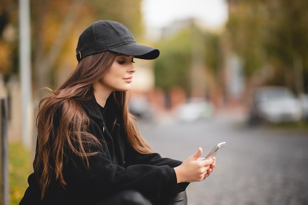 Linda garota em um boné de beisebol com um smartphone nas mãos