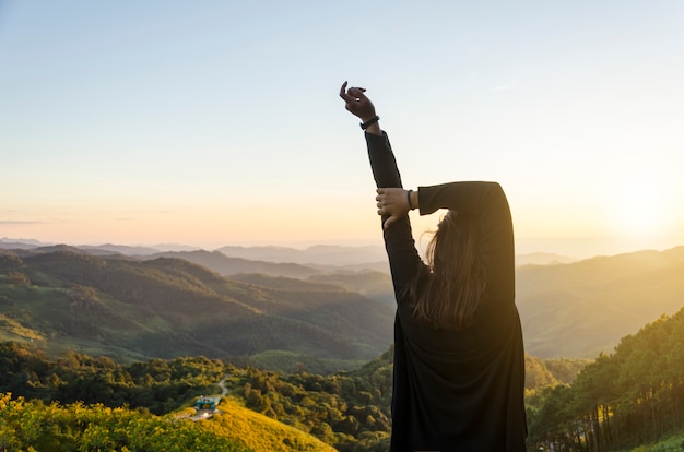 Foto linda garota em um campo de flor amarela ao pôr do sol