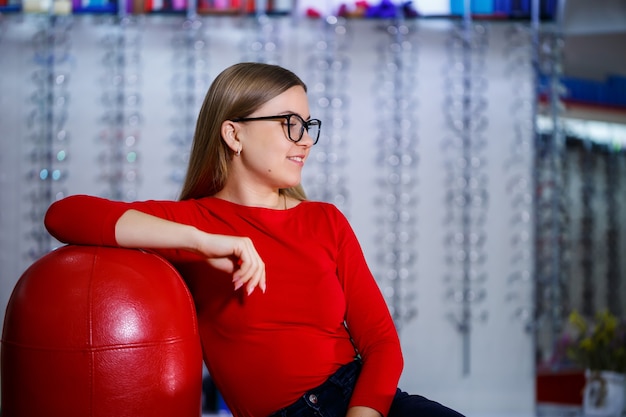 linda garota em um centro de oftalmologia pega óculos para correção da visão