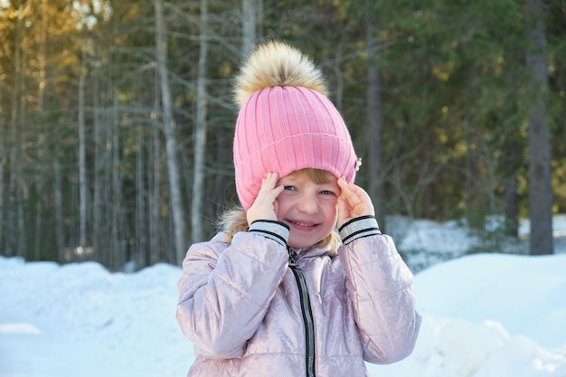 Linda garota em um dia ensolarado de inverno contra o pano de fundo de neve e floresta