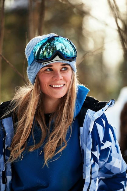 Linda garota em um terno de esqui azul e capacete Na cabeça estão óculos para snowboard Paisagem de montanha coberta de neve Retrato de um piloto Isso é o que a felicidade parece