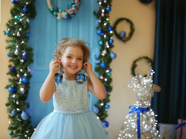 Linda garota em um vestido azul com bolas de Natal na véspera do feriado de 2022