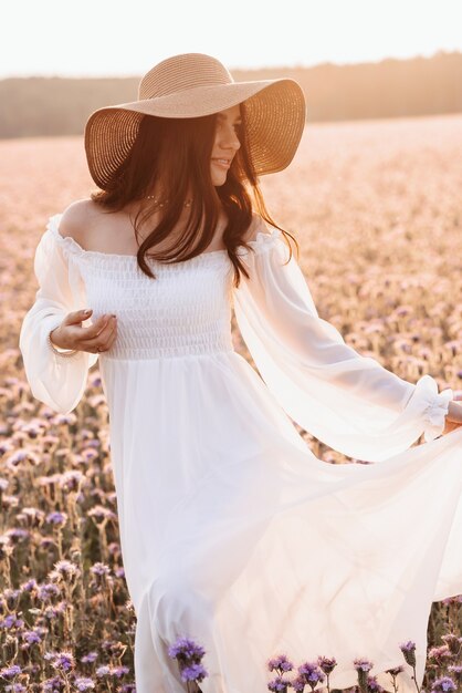 Linda garota em um vestido branco em um campo de lavanda ao pôr do sol.