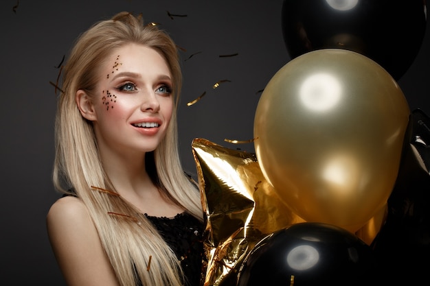 Linda garota em um vestido de noite elegante com balões festivos. Rosto bonito. Foto tirada no estúdio