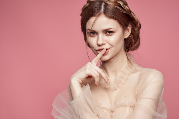 Linda garota em um vestido delicado sorrindo em um fundo rosa