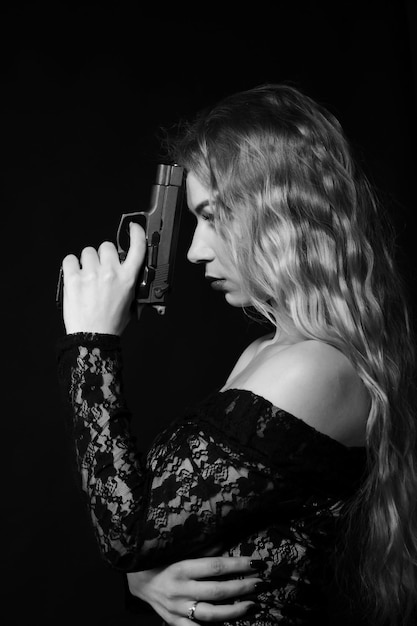 Linda garota em um vestido elegante. Mulher segurando uma arma nas mãos dela. foto preto e branco