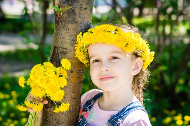 Linda garota em uma coroa de flores e com um buquê de flores na mão para passear no parque